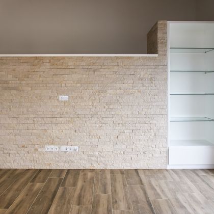 Móvel de estante com prateleiras de vidro embutido em parede de pedra